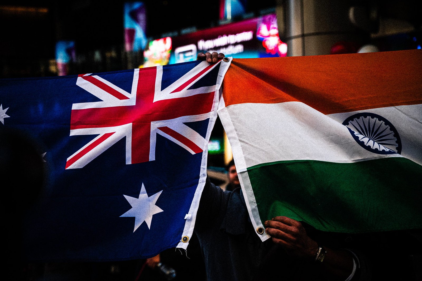 The Australian flag and the Indian tricolour held up together, anonymous hands beneath