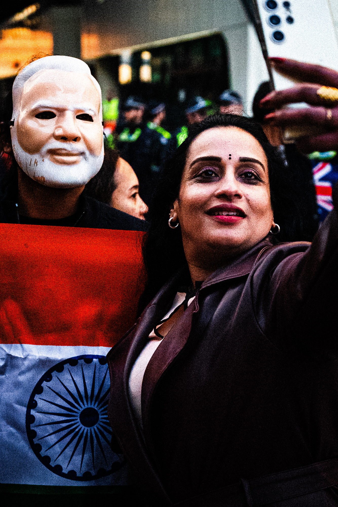 A woman takes a selfie beside someone wearing a Modi mask, the tricolour held across them both