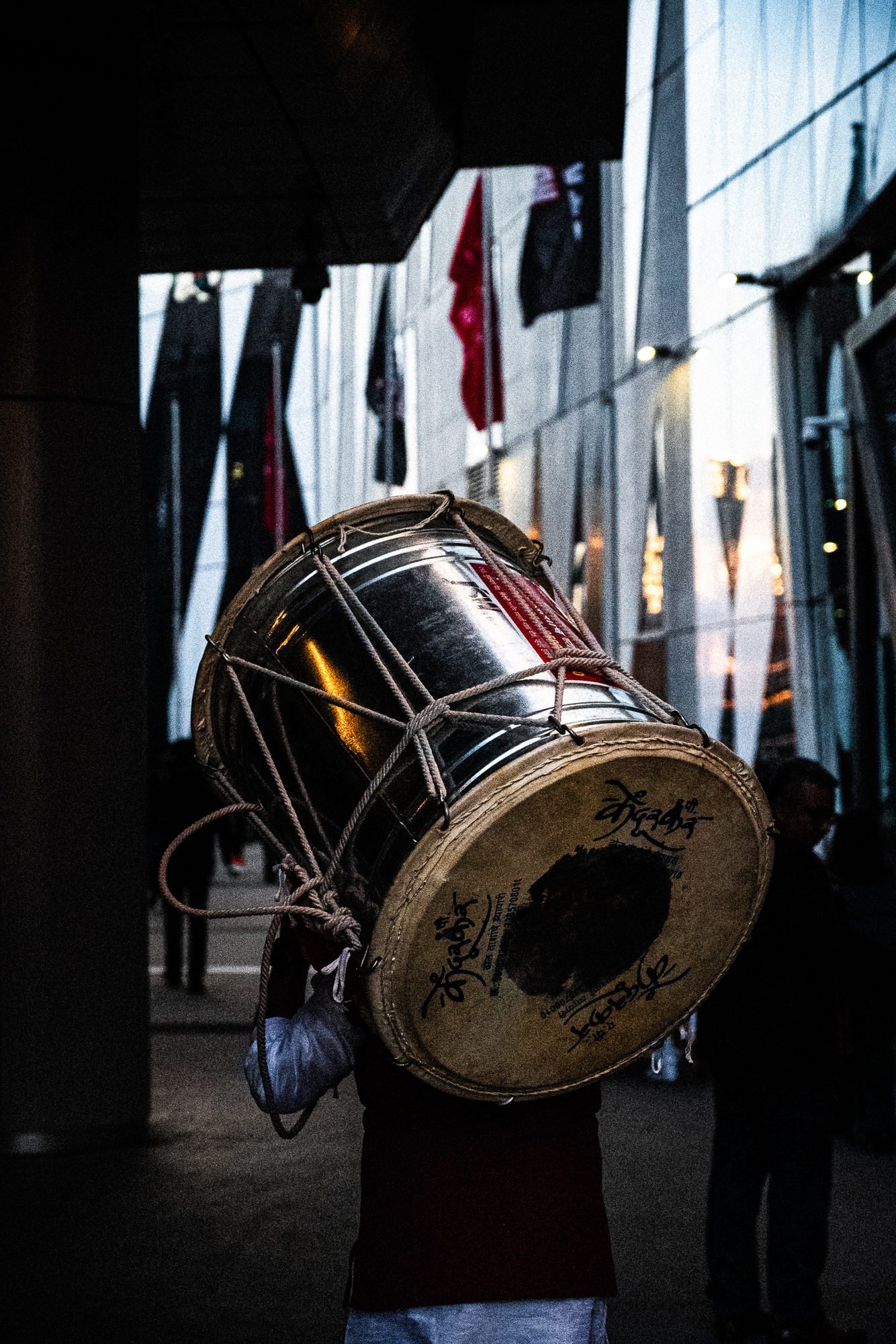 A dhol carried away on a shoulder at the end of the morning, writing visible on the drum skin